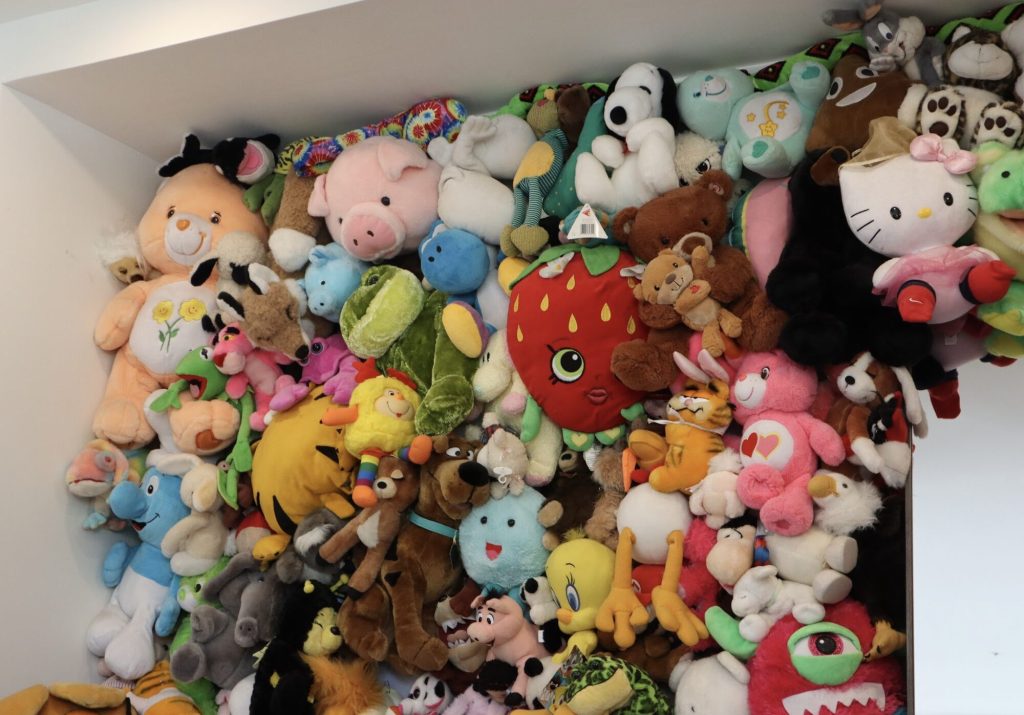 A whole bunch of stuffed animals pinned to a wall. The entire wall is covered. 