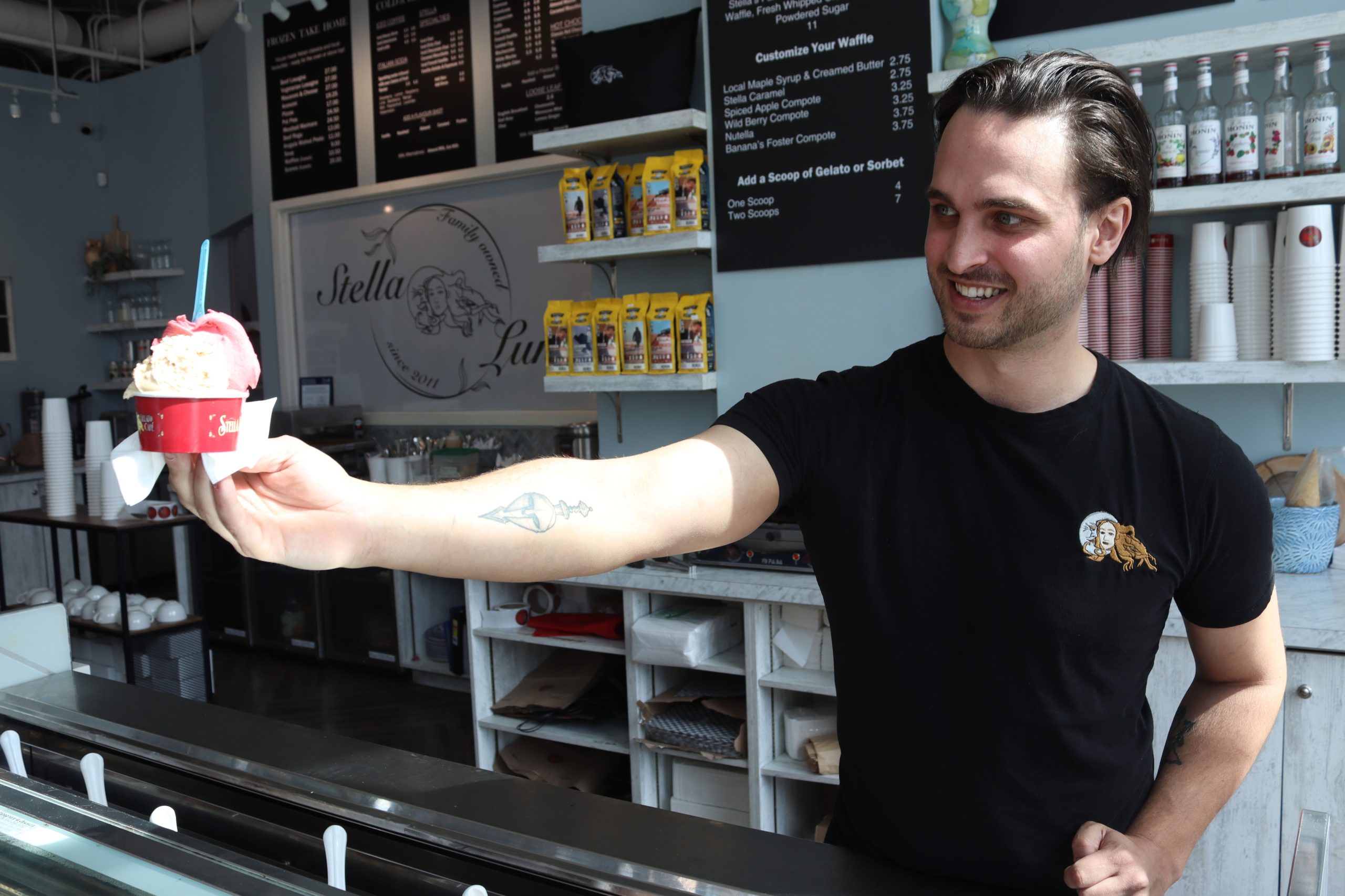 Zachary hands a bowl of gelato to a customer. 