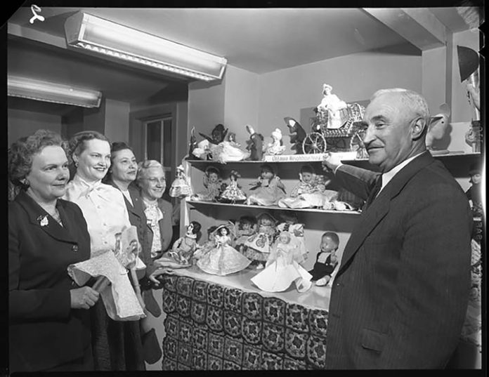 An old black and white photo showing people inspecting toys that have been fixed.