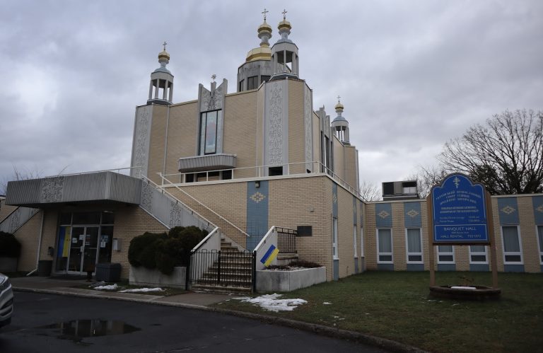 The exterior of the Assumption Of The Blessed Virgin Cathedral on Byron. The sky is grey and a small bit of snow is seen in the grass.