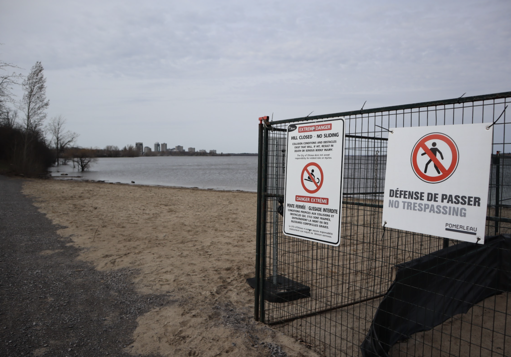 A sanded beach on a grey day. The water can be seen in the distance with construction fencing to the right.