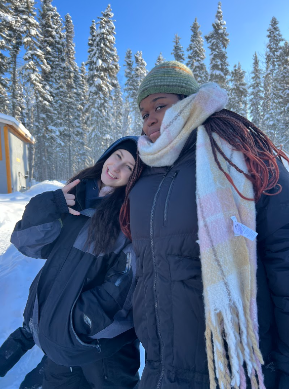 Two girls pose for a photograph outside on a sunny winter day.