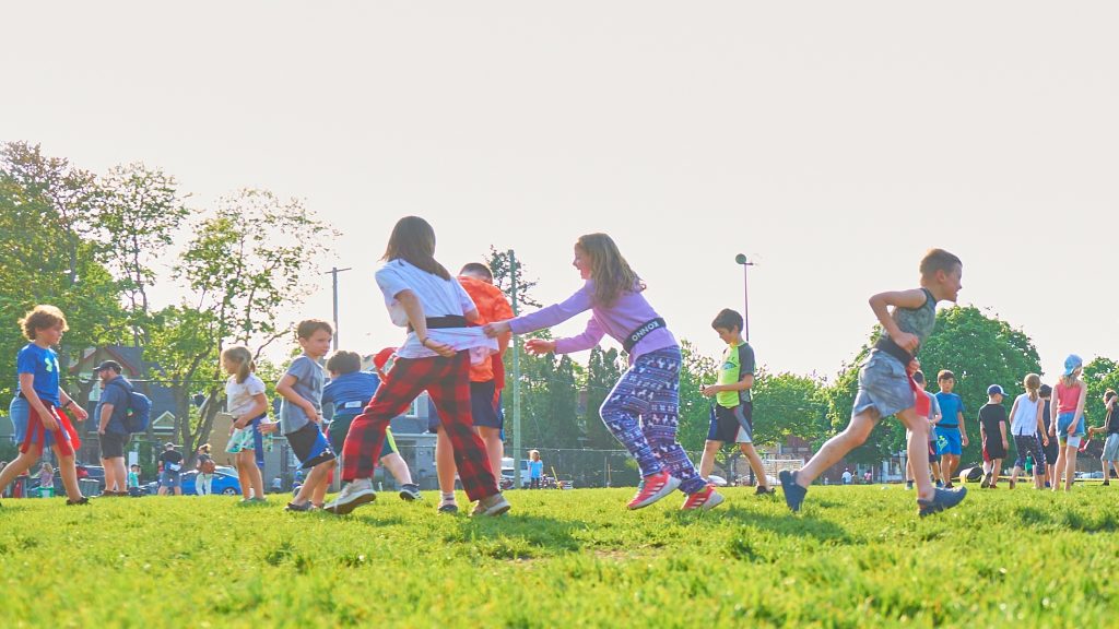 Kids run around on a sports field.