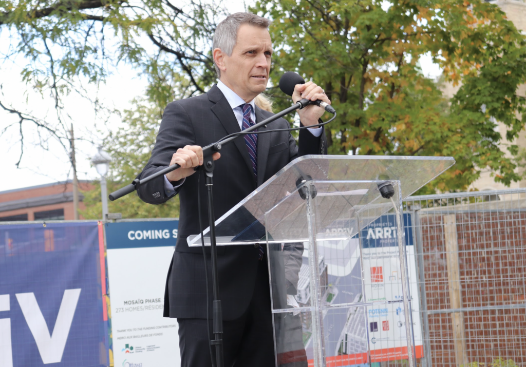 Mayor Mark Sutcliffe speaks at a podium. 