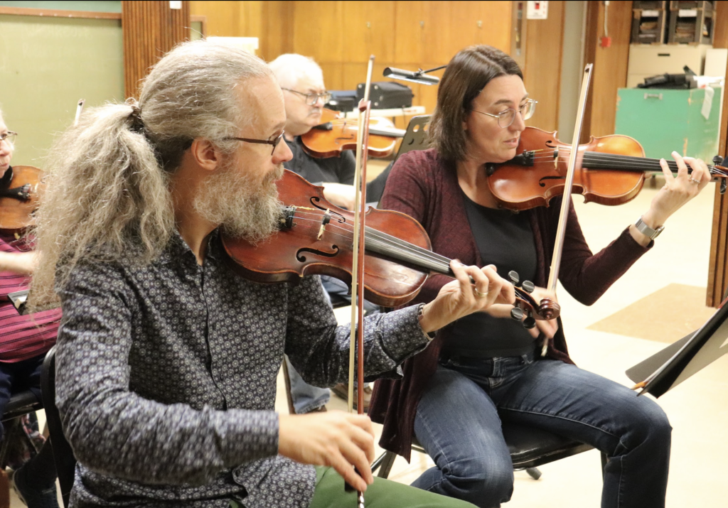 Two violin players are seen rehearsing. 