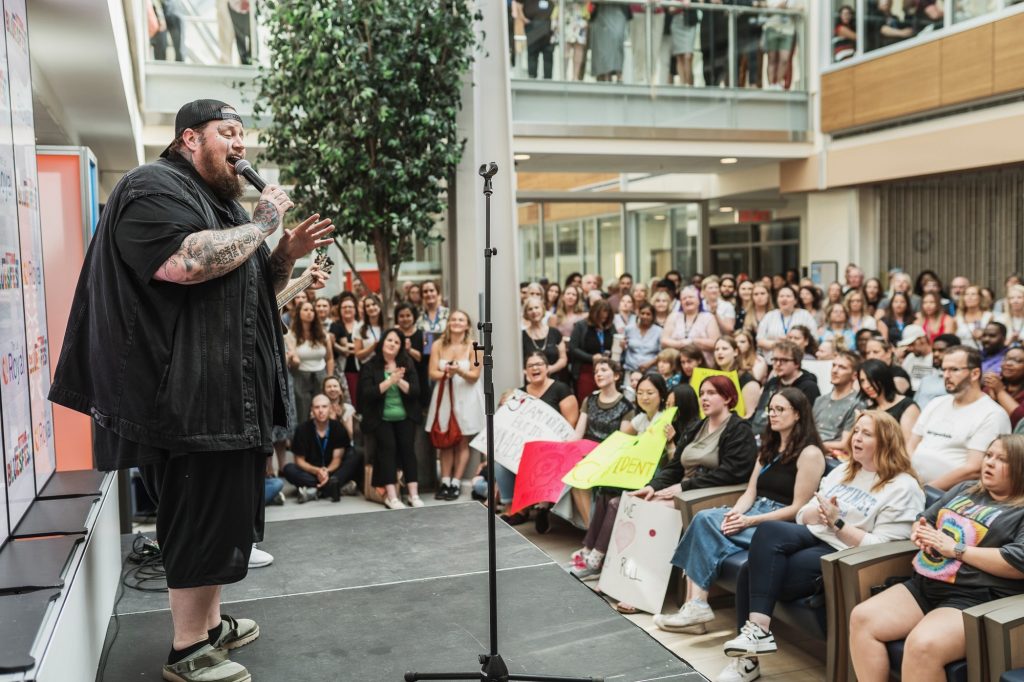 Jelly Roll sings on stage as people watch in the distance. 