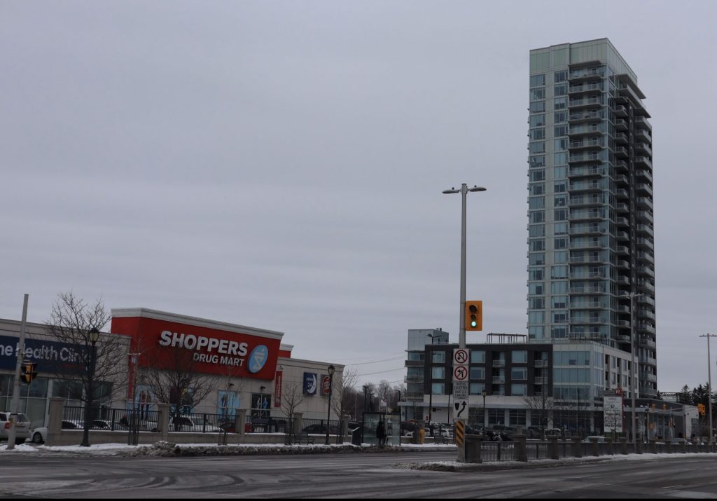 Shoppers drug mart seen on the left with an apartment building to the right. 