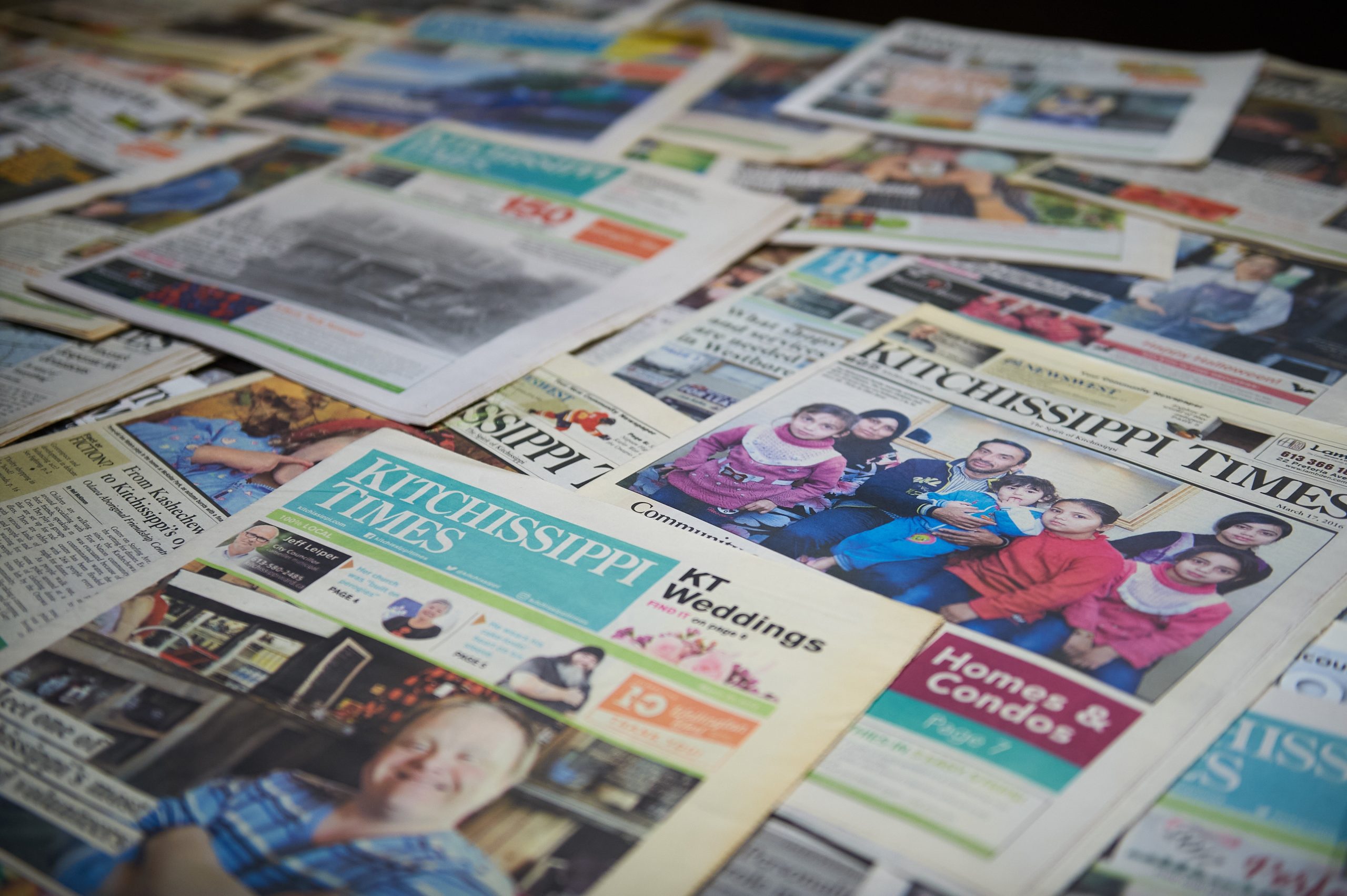 Many newspapers sit on a table. 