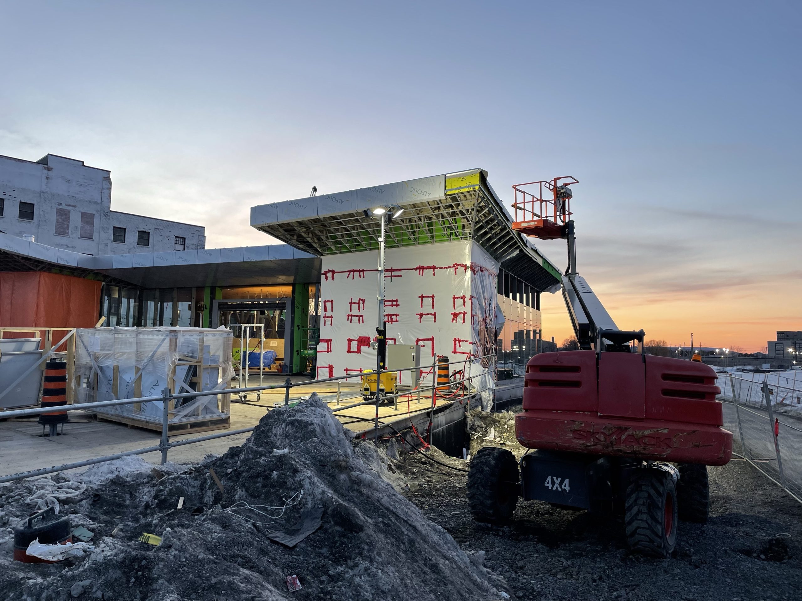 The exterior of the unfinished Gladstone LRT station. The sun is setting in the background.