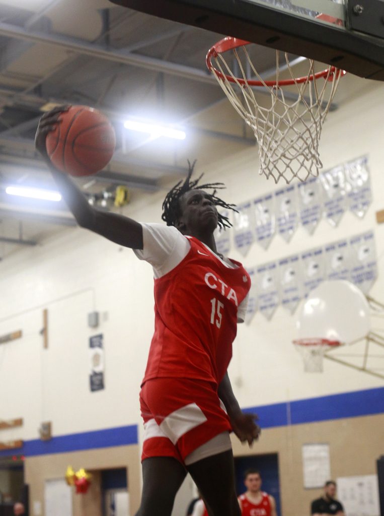 A Black basketball player dunks a basketball into the net. 