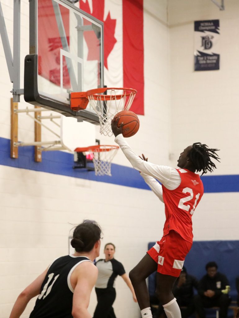 A basketball player wearing red dunks a ball into the net. 