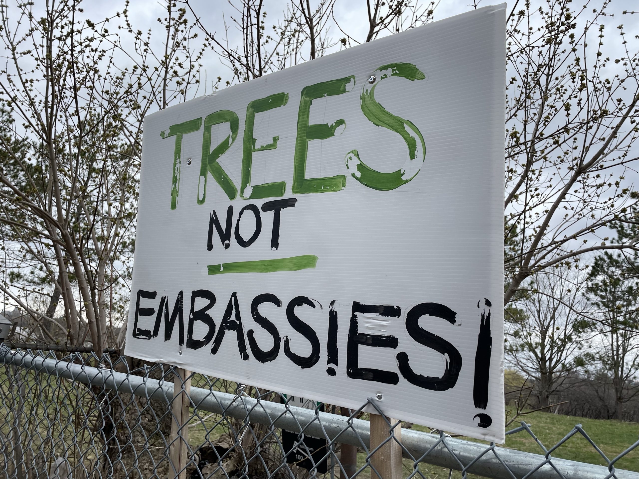 A sign reading “Trees not Embassies” sits at the front gate to the park.