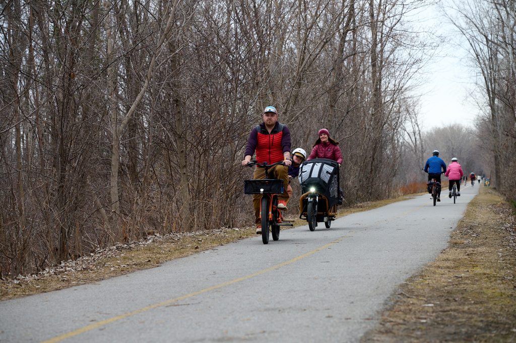 Thr family rides their bike down a path. 