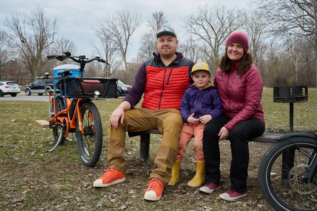 A family of three poses for a photo with their two bikes. 