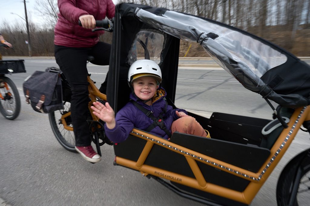 A child waves while he’s in a bike. 