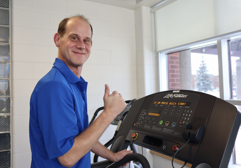 Dylan Harries holds a thumbs up as he poses for a photograph on a treadmill.