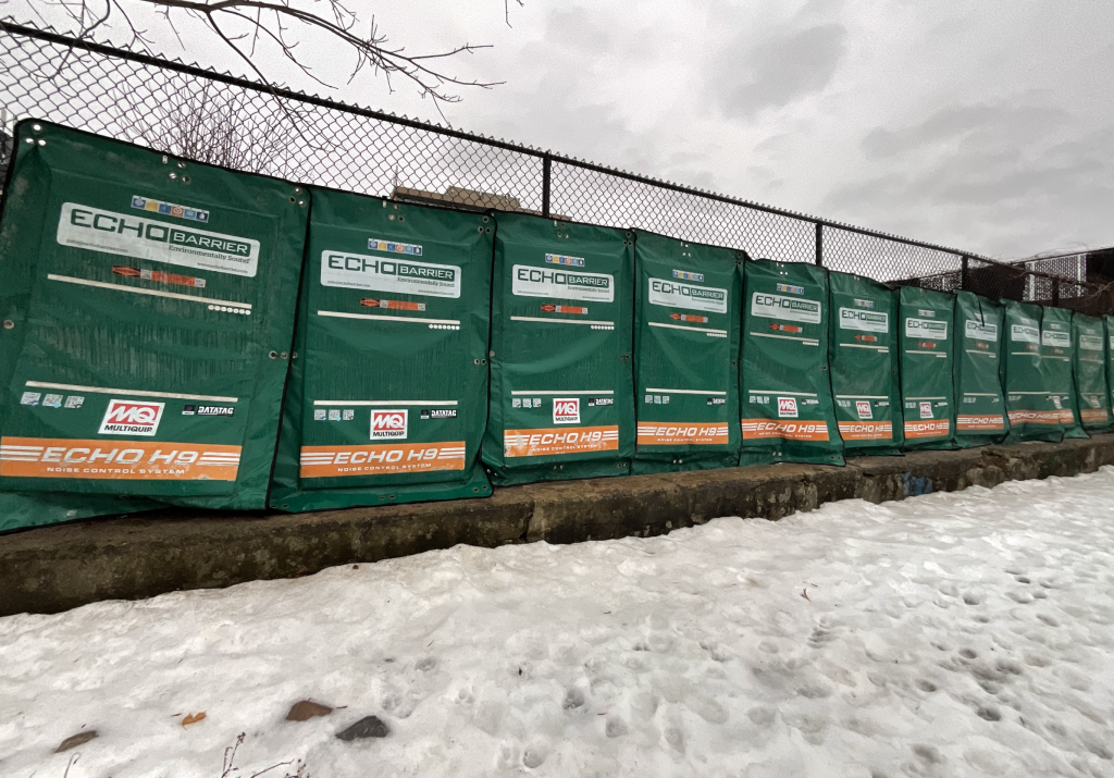 Green sound barriers attached to a fence outside of Devonshire Public School