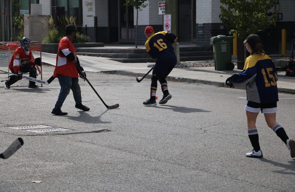 Kids play ball hockey on the street. 