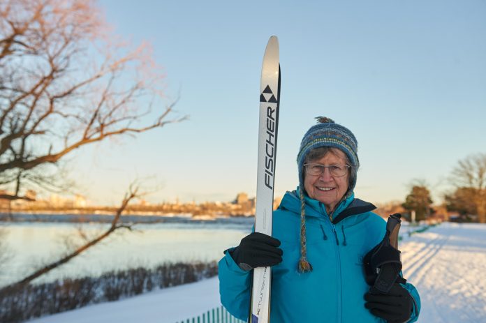 A photo of Linda posting with her cross country skis on the Kichi Sibi winter trail.