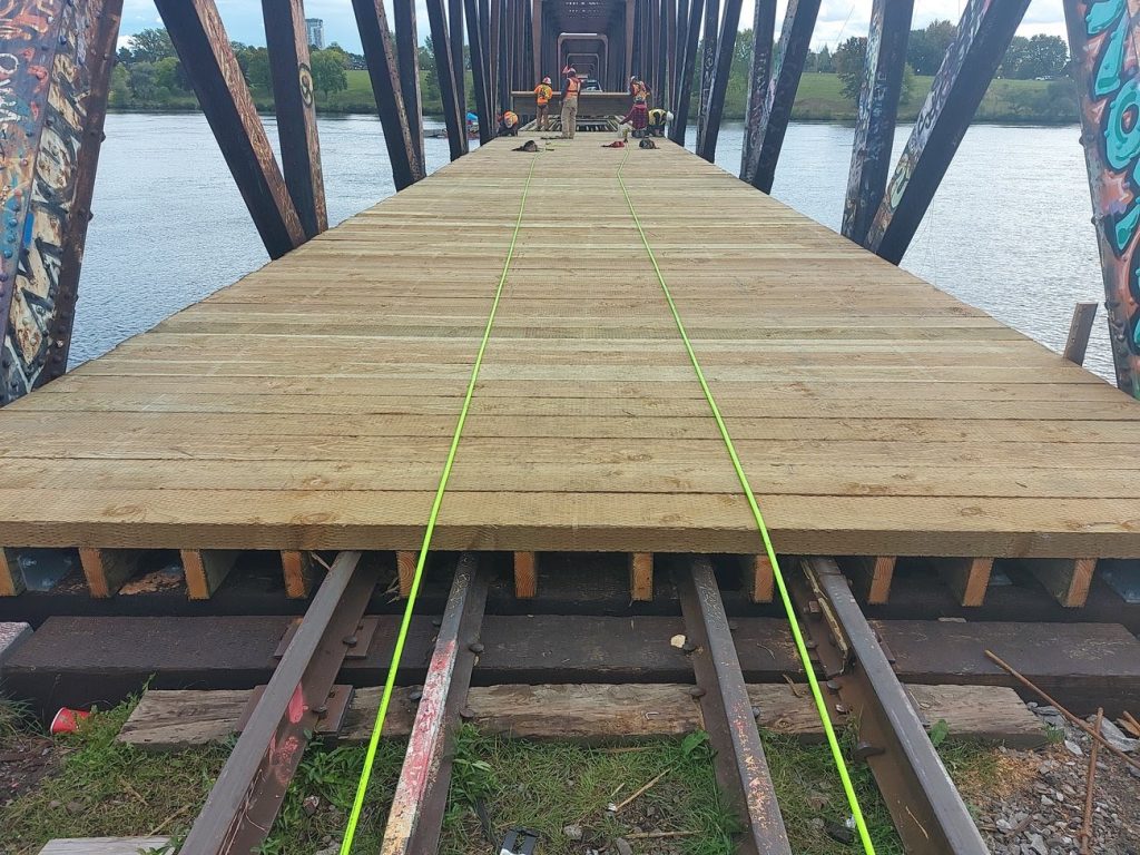 Workers install a wooden pathway over a former rail bridge. 