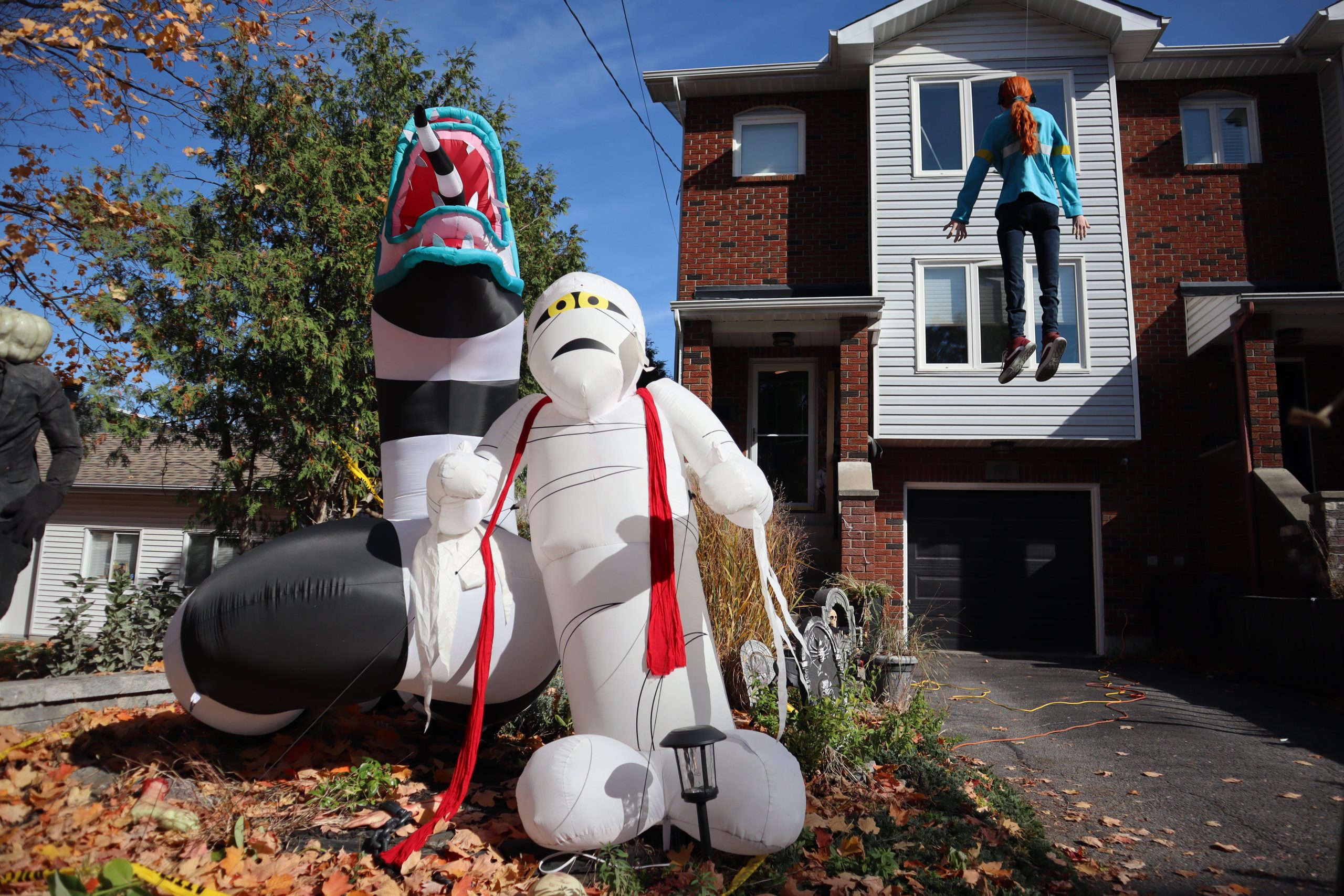 A dragon, mummy, and a styrofoam body of Stranger Things Character Max Mayfield is on display outside of a home for Halloween