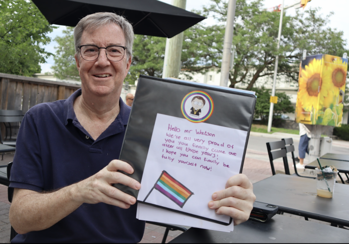 Jim Watson smiles as he holds up the binder.