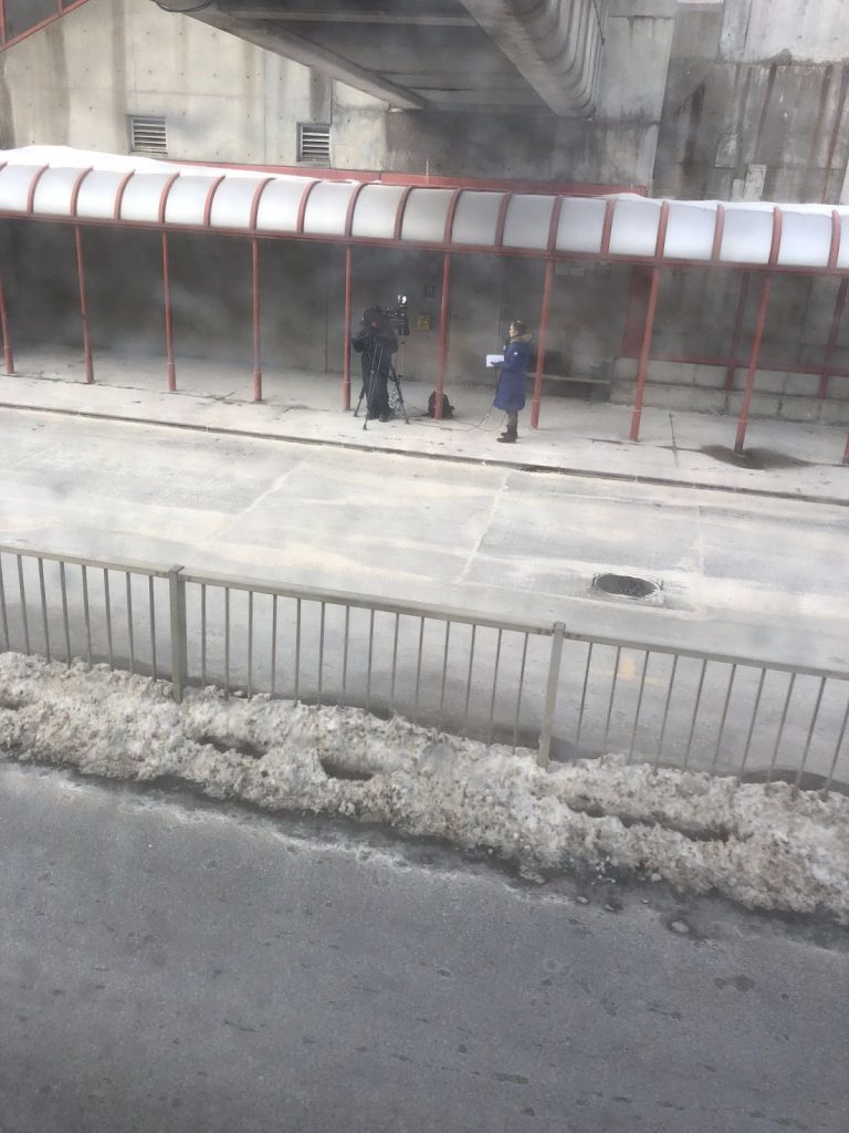 The Westboro bus station is seen from a distance with two reporters on site three days after the crash