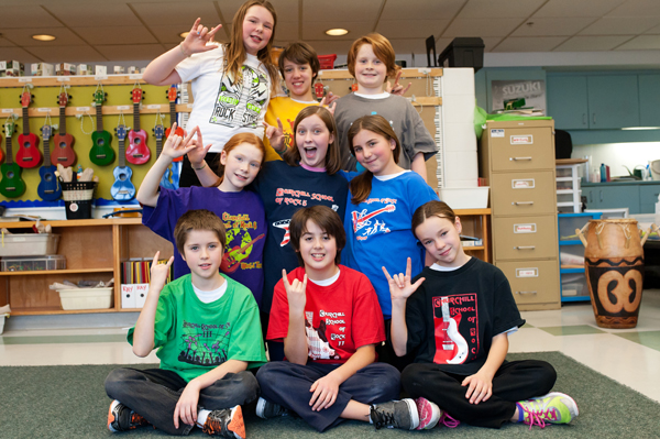 Churchill students show off the different School of Rock t-shirt designs over the years. Photo by Kate Settle