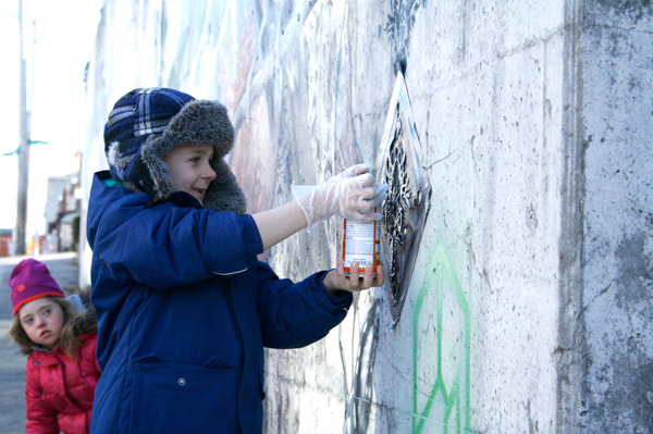 Hintonburg residents, including Noah Parsons, added some finishing touches to the new mural. Photo by Jacob Hoytema