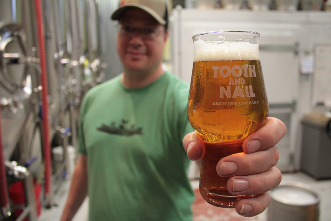 Tooth and Nail Brewing Company’s founder Matt Tweedy displays a glass of Rabble Rouser IPA at their combination brewery and pub on 3 Irving Ave.