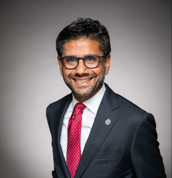 A professional photo of Yasir Naqvi against a gradiant grey and white background.