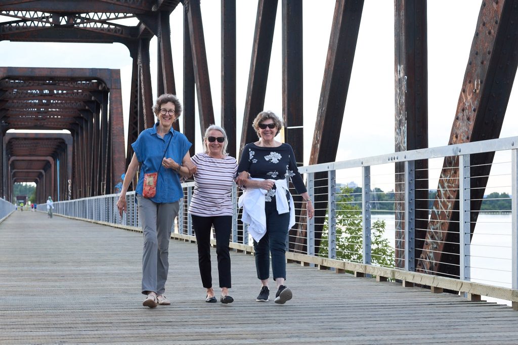 Three women link arms and cross over the Chief William Commanda Bridge.