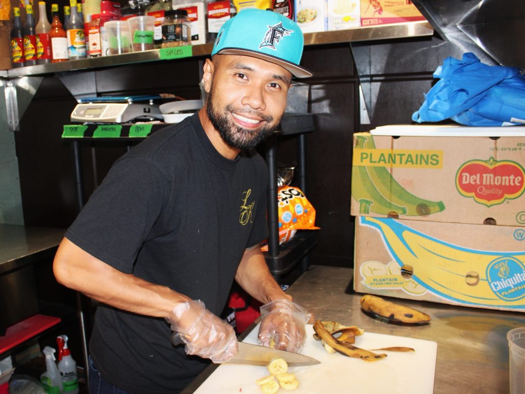 A man cuts bananas in a kitchen.