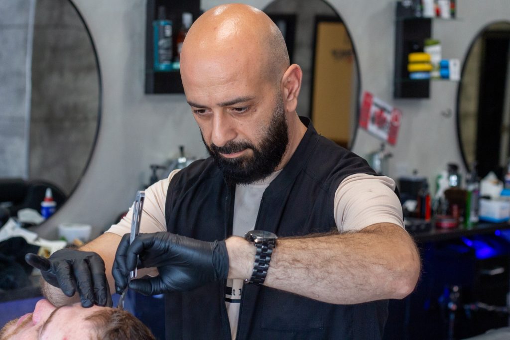 Alaa gives a haircut to a man.