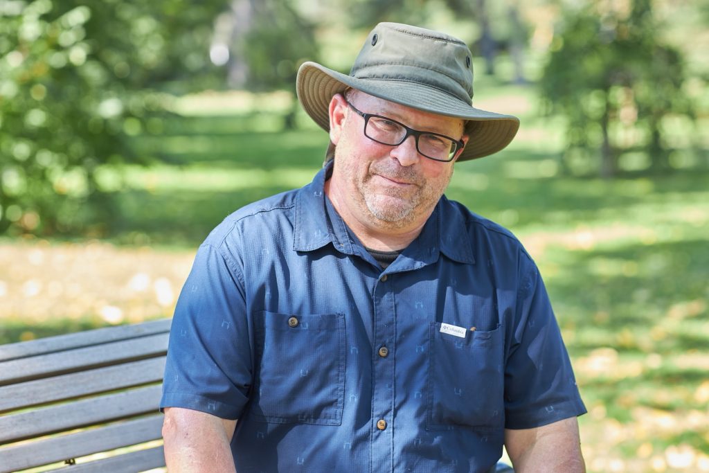 Robert poses for a photo on a bench.