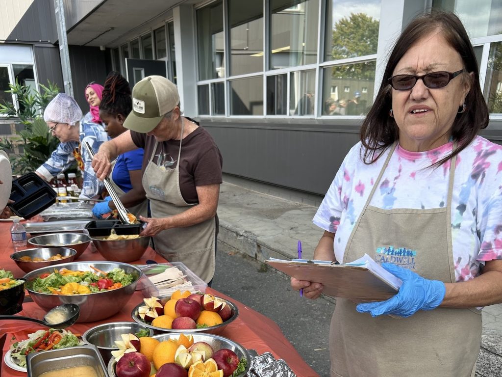 A group of people serve up fresh food outside.