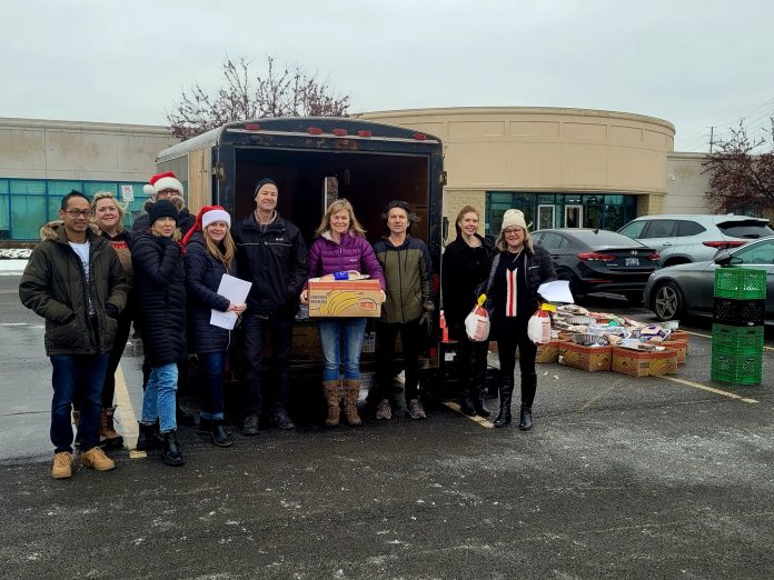 A group of people stand with boxes of donated food.