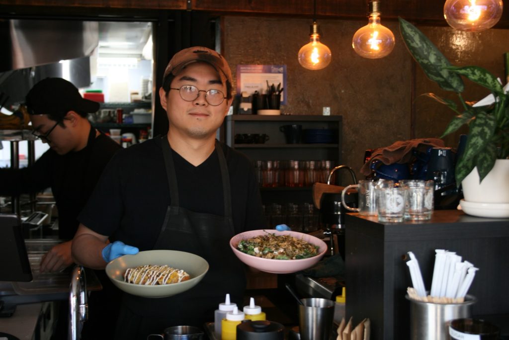 James holds up two dishes he cooked.