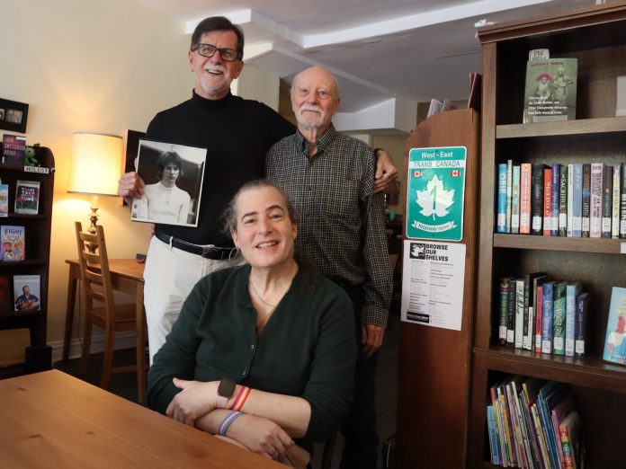 A group of three people sit in a library.