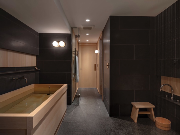 A bathroom with black tiles and wooden fixture’s.